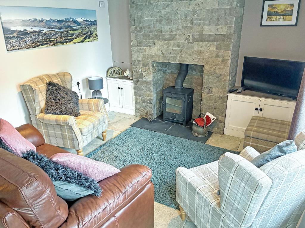 a living room with couches and a stone fireplace at Cosy Cottage in Portinscale