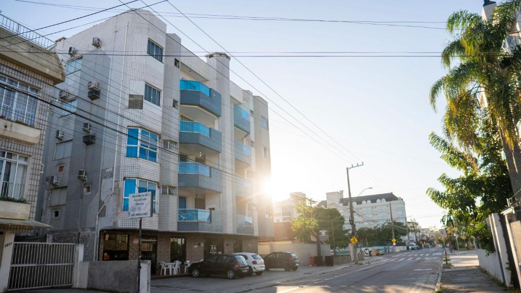 a building on a city street with the sun setting at Monte Libano Apart Hotel in Florianópolis