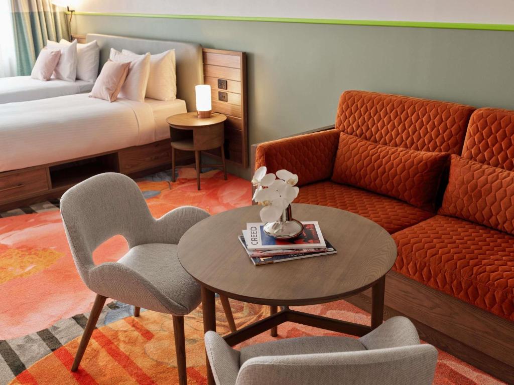 ein Hotelzimmer mit Sofa, Tisch und Stühlen in der Unterkunft The Clarence Hotel Sydney in Sydney