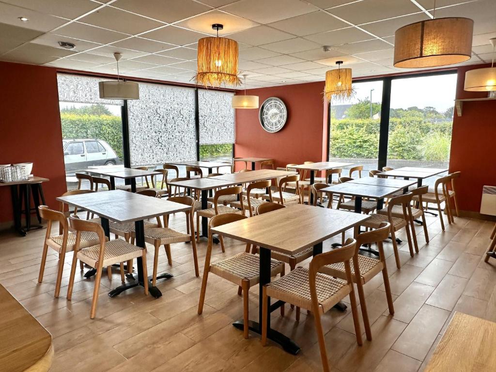 a restaurant with wooden tables and chairs and windows at Best Western Hotel de la plage Normandie in Asnelles