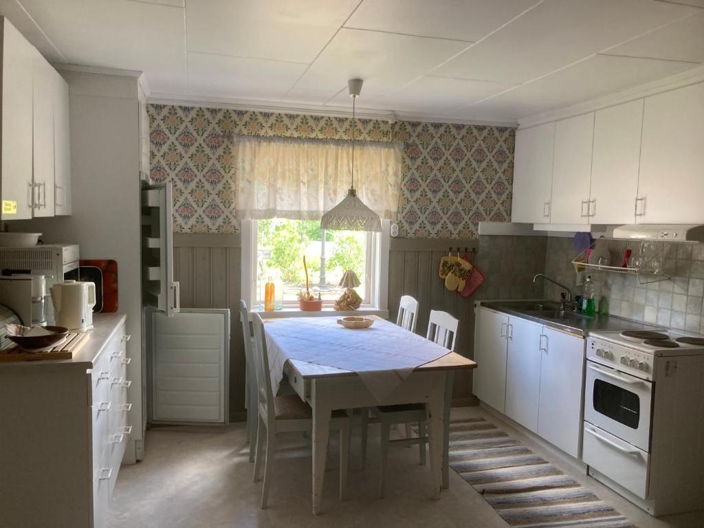 a white kitchen with a table and a window at Liten lägenhet i Öje in Öje