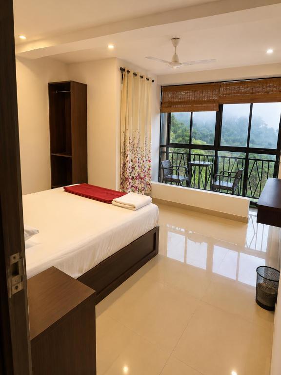 a bedroom with a bed and a balcony at Grand Munnar Rooms in Munnar