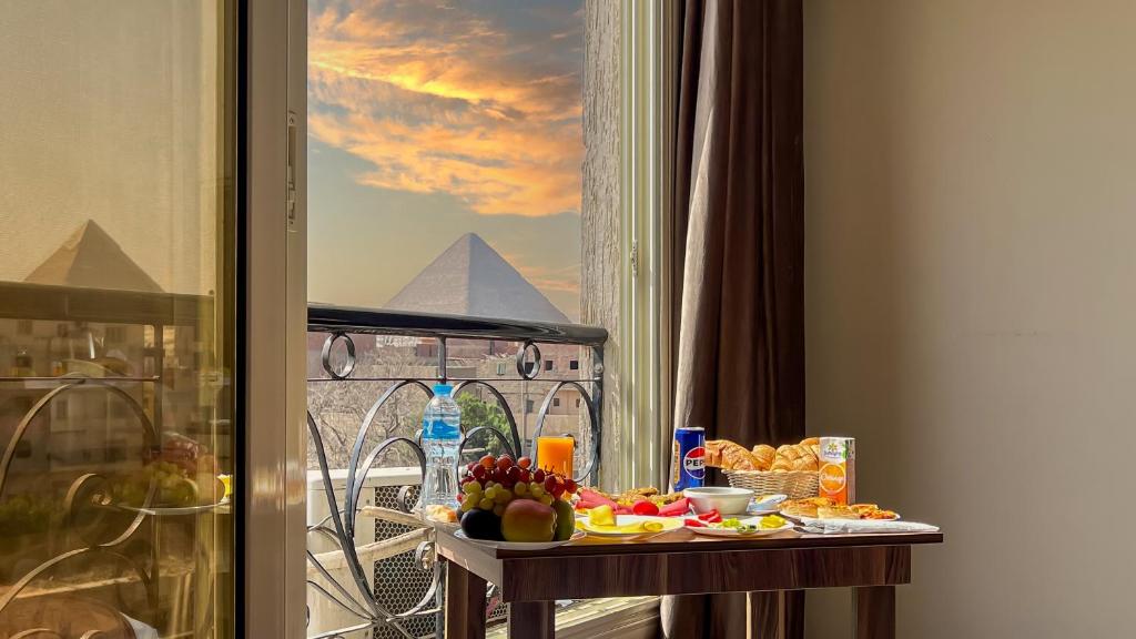 a table with food on a balcony with a view of the pyramid at Hammis Pyramids View INN in Cairo