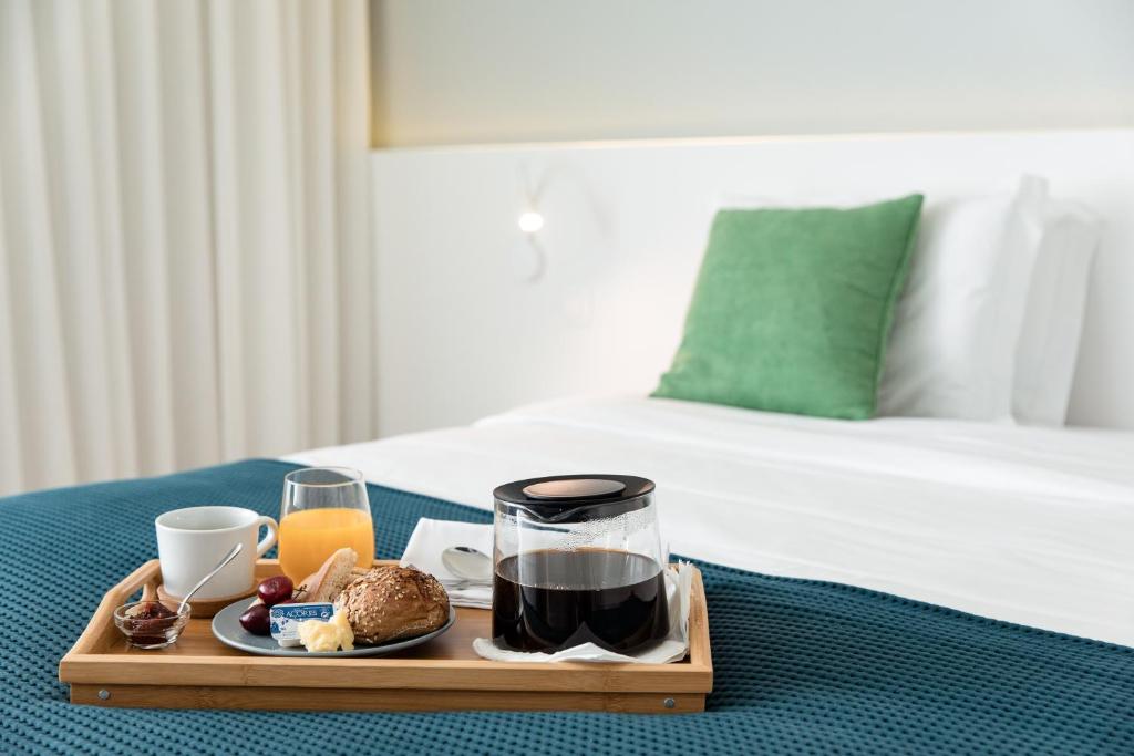 a tray of breakfast food on a table next to a bed at Ilha Hostel & Suites in Ponta Delgada