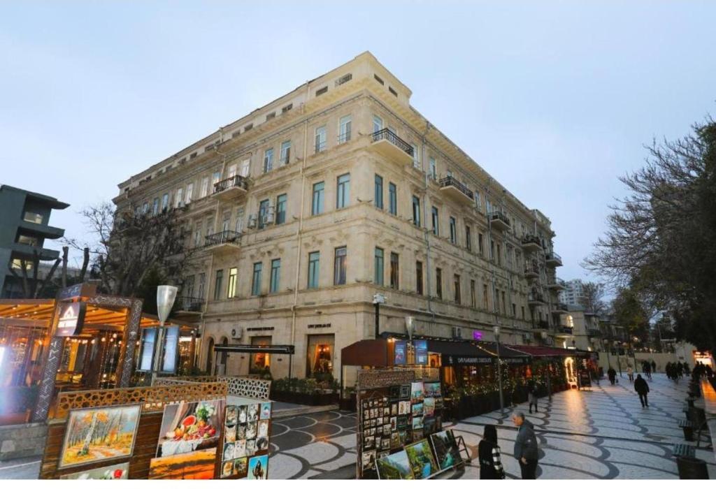 ein Gebäude an einer Straße, vor dem Menschen entlanggehen in der Unterkunft Azcot Hotel in Baku