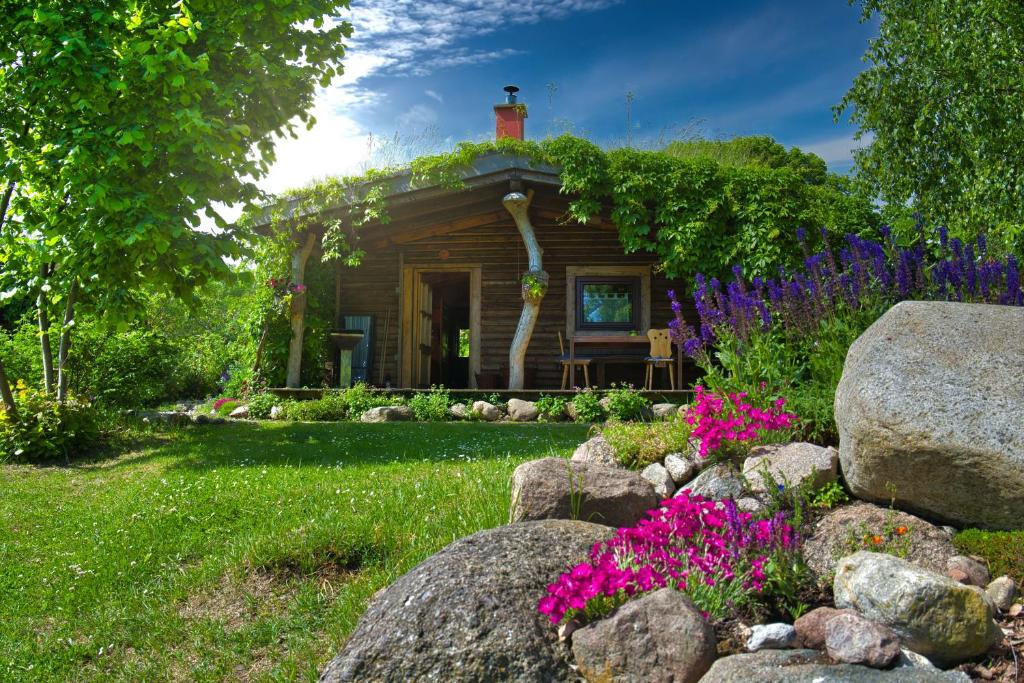 a small cabin with flowers in the yard at Idyllisches Blockhaus Mecklenburger Seenplatte in Penzlin