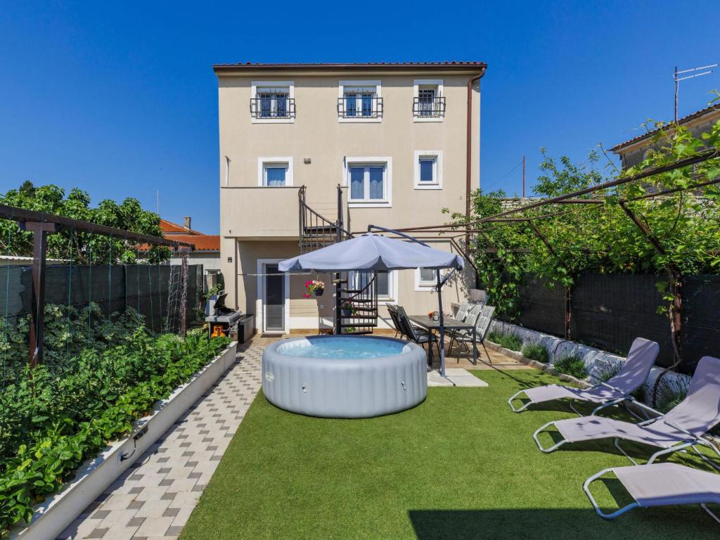 a backyard with a pool with chairs and an umbrella at Apartment L&V by Interhome in Galižana