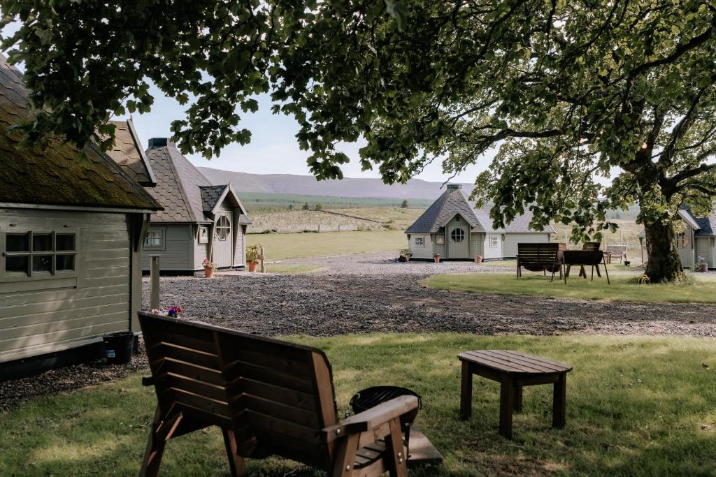 a park bench sitting under a tree with houses in the background at Scald Law Cabin in Kirknewton