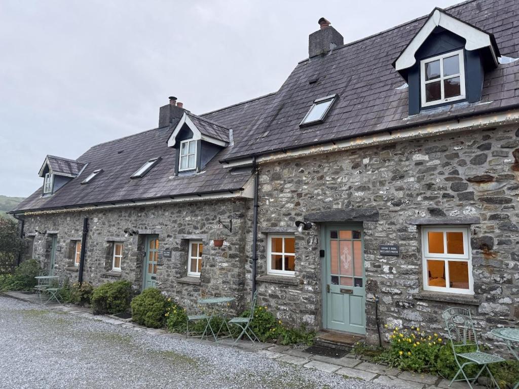 an old stone house with a green door and windows at Abbey Cottages Buzzards Watch in Talley