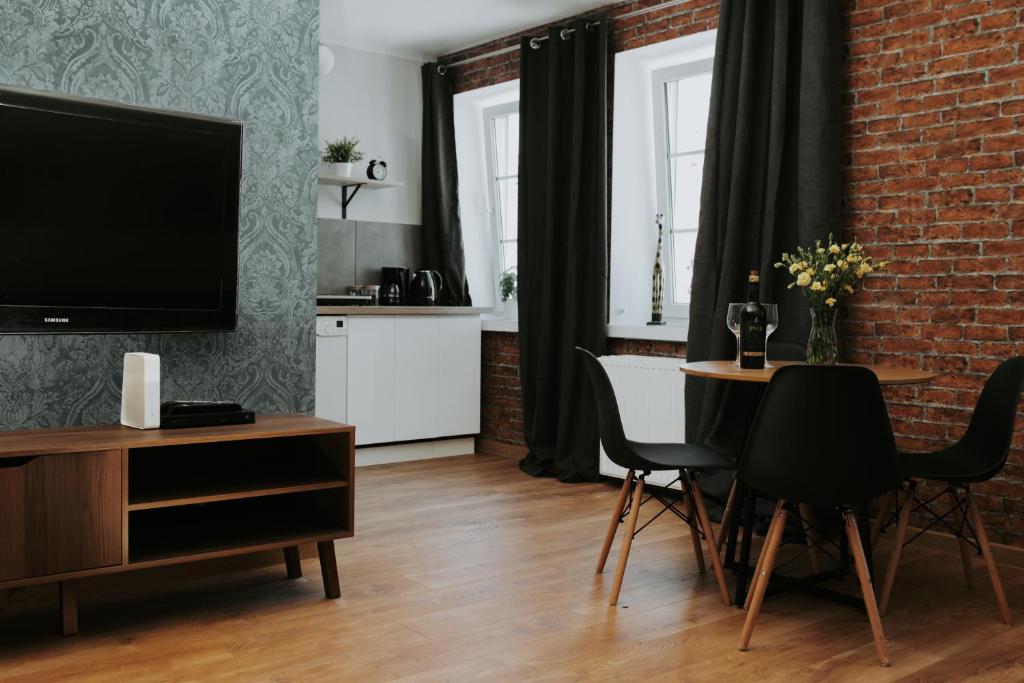 a living room with a television and a table with chairs at Złota Brama - Old Town Apartament 2 in Gdańsk
