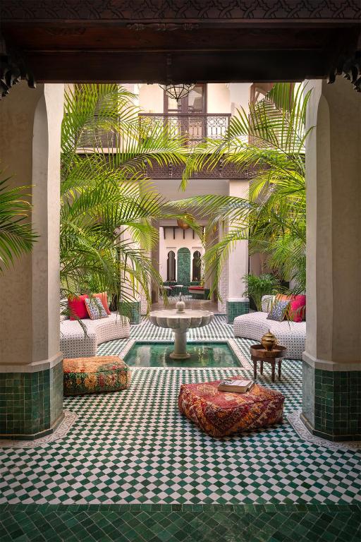 a courtyard with a fountain in a building with palm trees at Riad Dar des Arts in Marrakesh