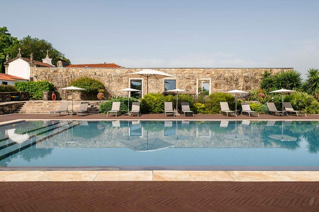 a large swimming pool with chairs and umbrellas at Hotel Paço de Vitorino in Ponte de Lima