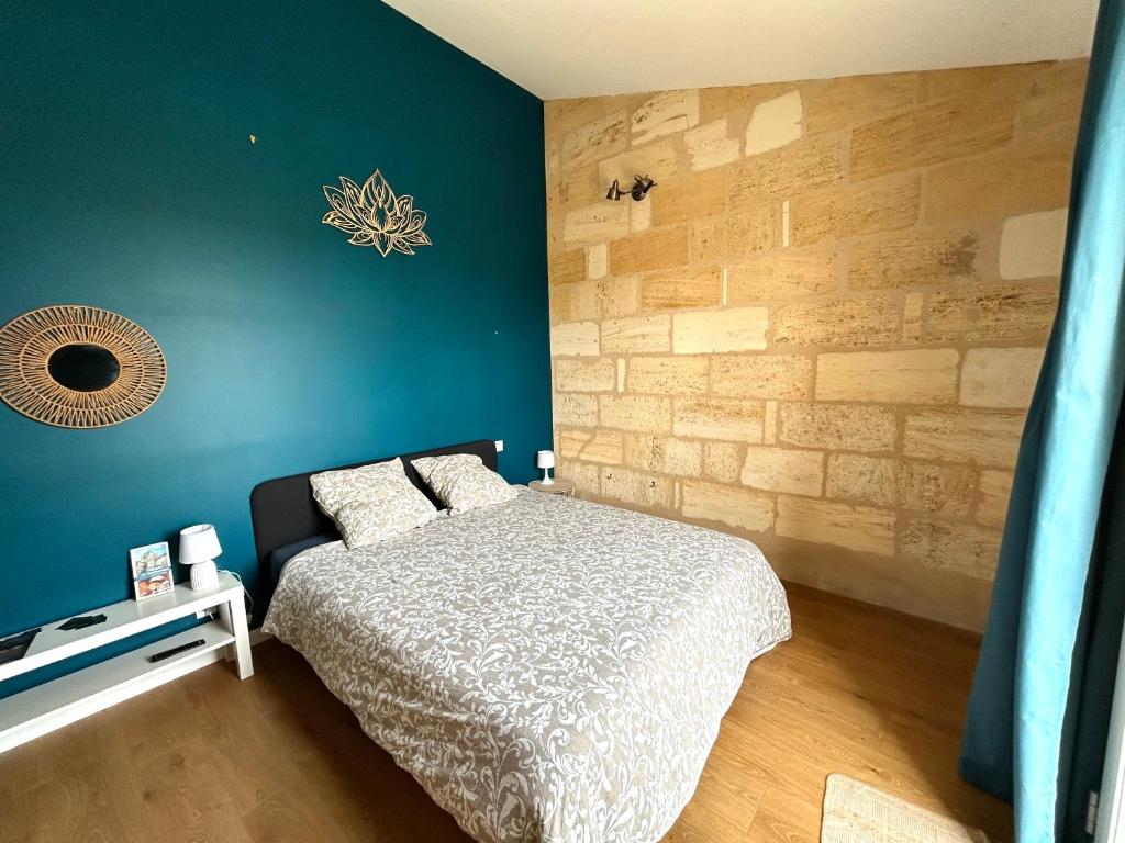 a bedroom with a bed and a blue wall at Logis des vignes in Saint-Émilion