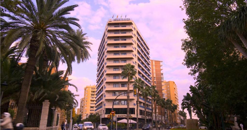 a tall building on a city street with palm trees at Hotel MS Maestranza Málaga Centro in Málaga