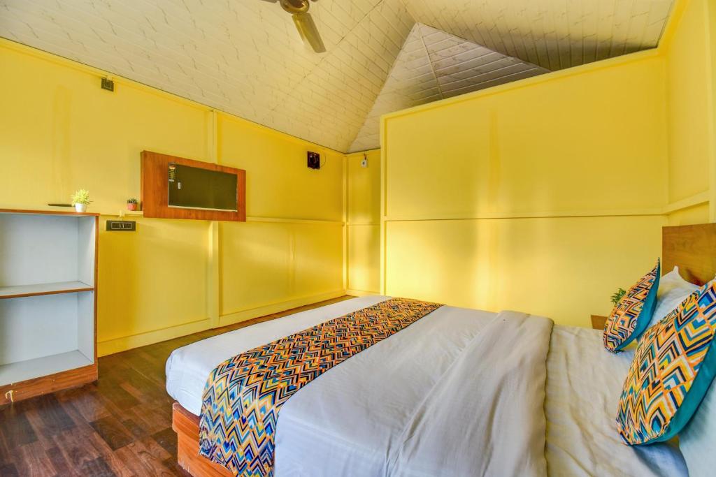 a bedroom with a bed and a yellow wall at Hotel Briko Lodging & Resort in Nashik