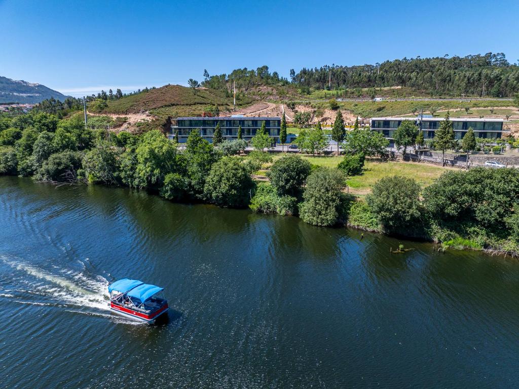 a boat traveling down a river with at Lima Riverview Suites in Ponte de Lima