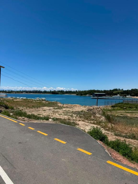 an empty road next to a body of water at All Home in Cholpon-Ata