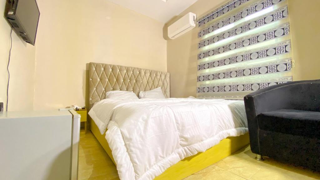 a bedroom with a bed and a window and a chair at H&Ts Bars and Hotels in Ibadan