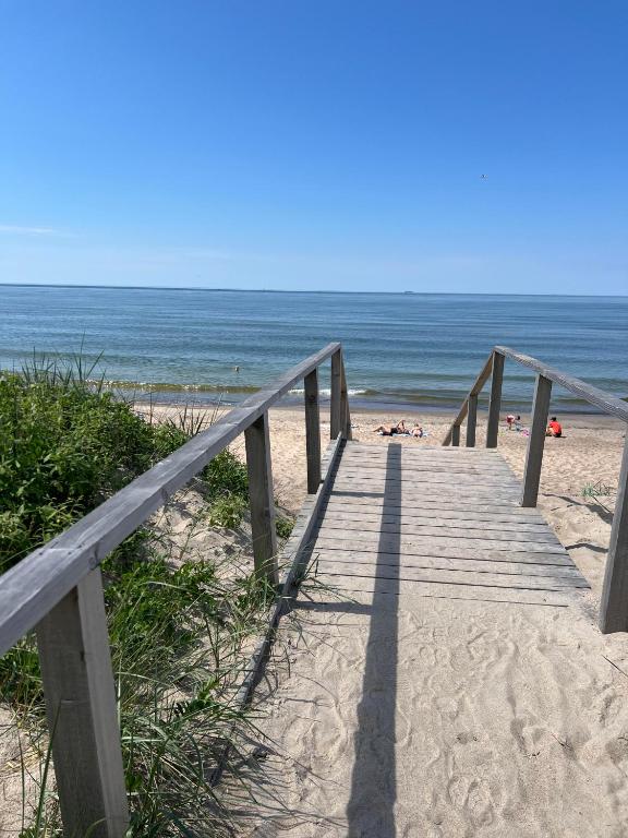 a wooden boardwalk leading to a beach with the ocean at Melnragė Dunes Apartment in Melnragė