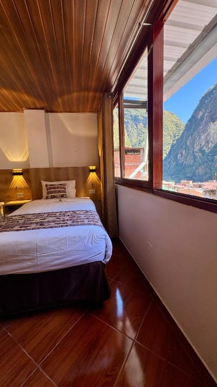 a bedroom with a bed and a large window at Apachetas Hotel in Machu Picchu