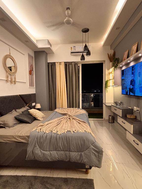 a bedroom with a large bed and a flat screen tv at The cozy corner in Ghaziabad