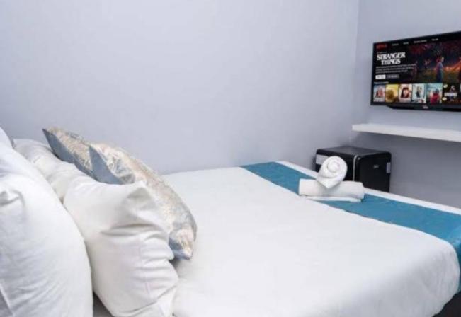 a bedroom with a bed with white pillows and a tv at Blue aura in Kuala Lumpur
