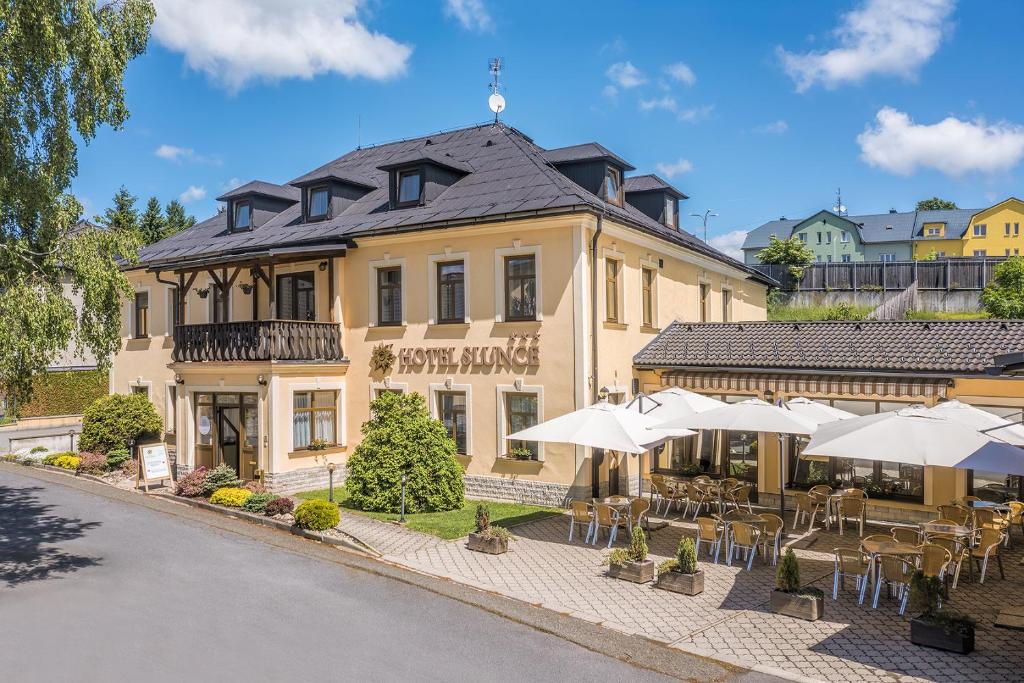 a building with tables and umbrellas in front of it at Hotel Slunce - wellness s bazénem, pivovar Morous a bowling in Rýmařov