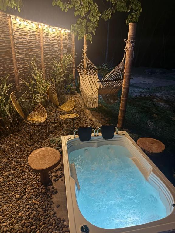 a hot tub in a yard with chairs and a hammock at Palmar el descanso bruma del balsal in Villeta