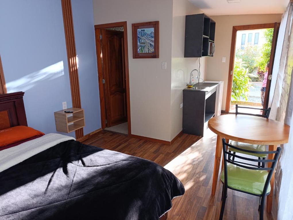 a bedroom with a bed and a table and a kitchen at Hospedaje Carigan in Loja
