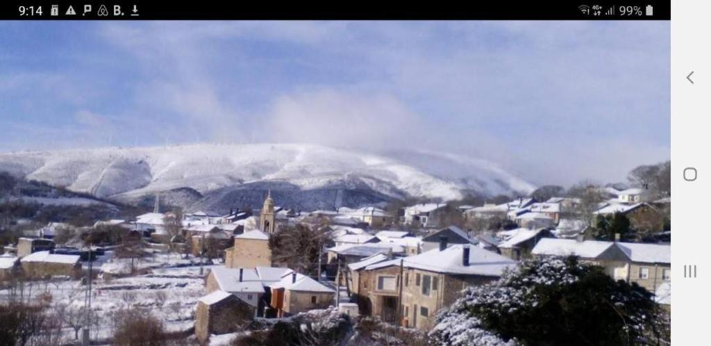 a town covered in snow with a mountain in the background at Casa Rústica Mariana in Lubián