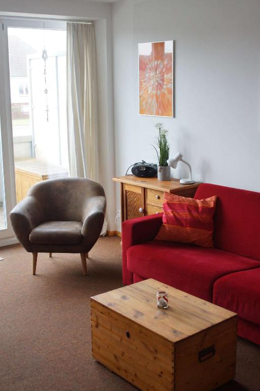 a living room with a red couch and a chair at Nordnordwest in Langeoog