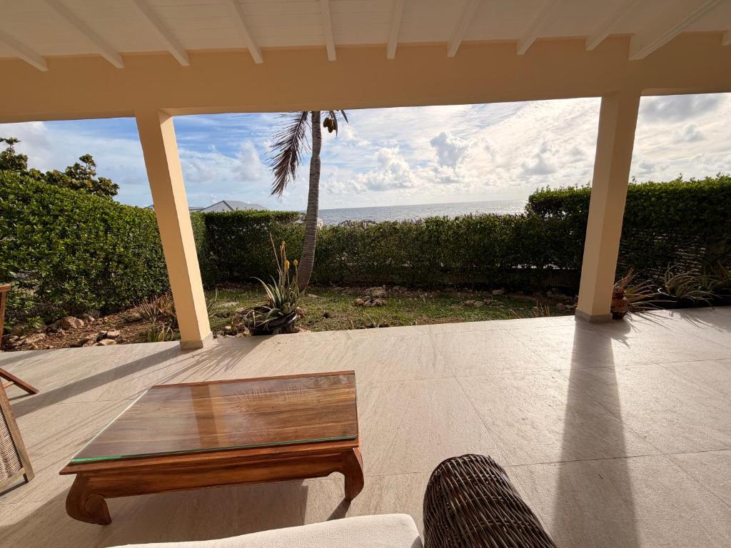 a patio with a table and a view of the ocean at Villa JAUNE in Oyster Pond