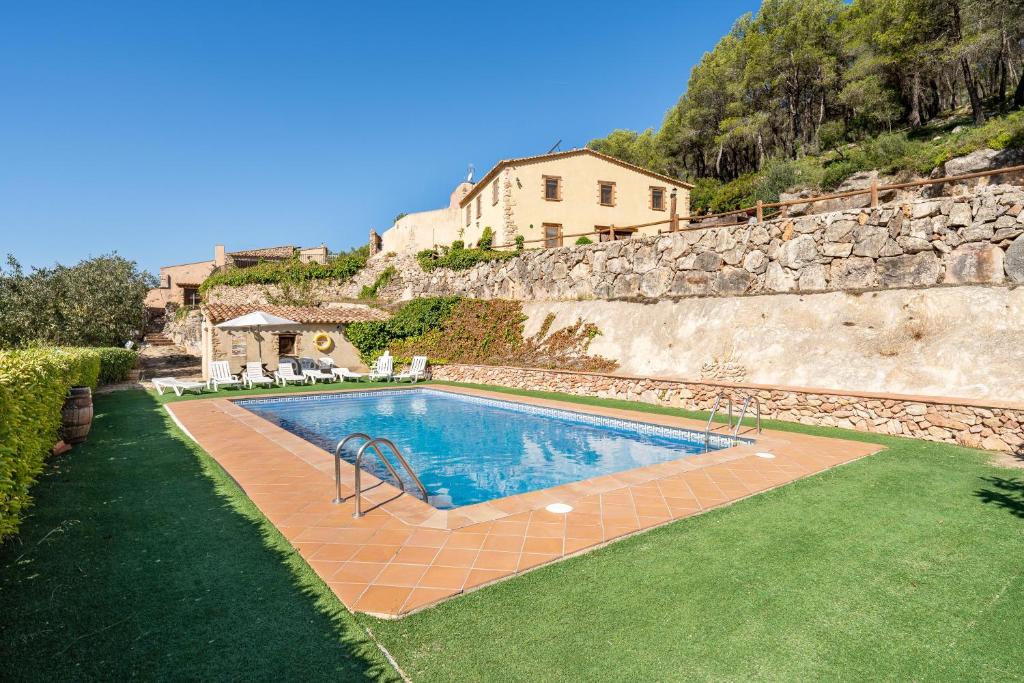 a swimming pool with a house in the background at Masia Puigadoll in Rodonyà