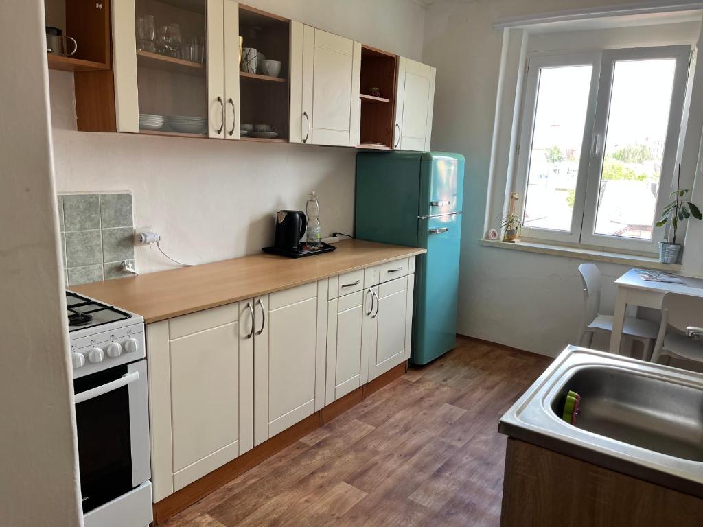 a kitchen with white cabinets and a blue refrigerator at Máneska in Cheb