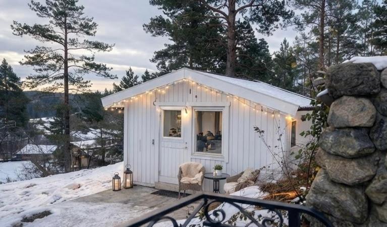 a small white shed with lights on it in the snow at Naturstugan in Nacka in Ormingelandet