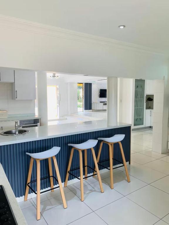 a kitchen with three bar stools and a counter at Monti's Villa Suites in Southgate
