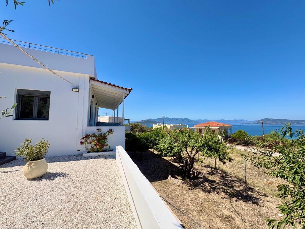 a white house with a view of the ocean at The Izi House in Egina