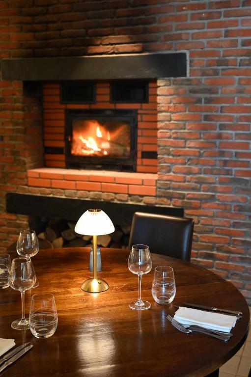 a wooden table with wine glasses and a fireplace at Au Bon Gîte in Senones
