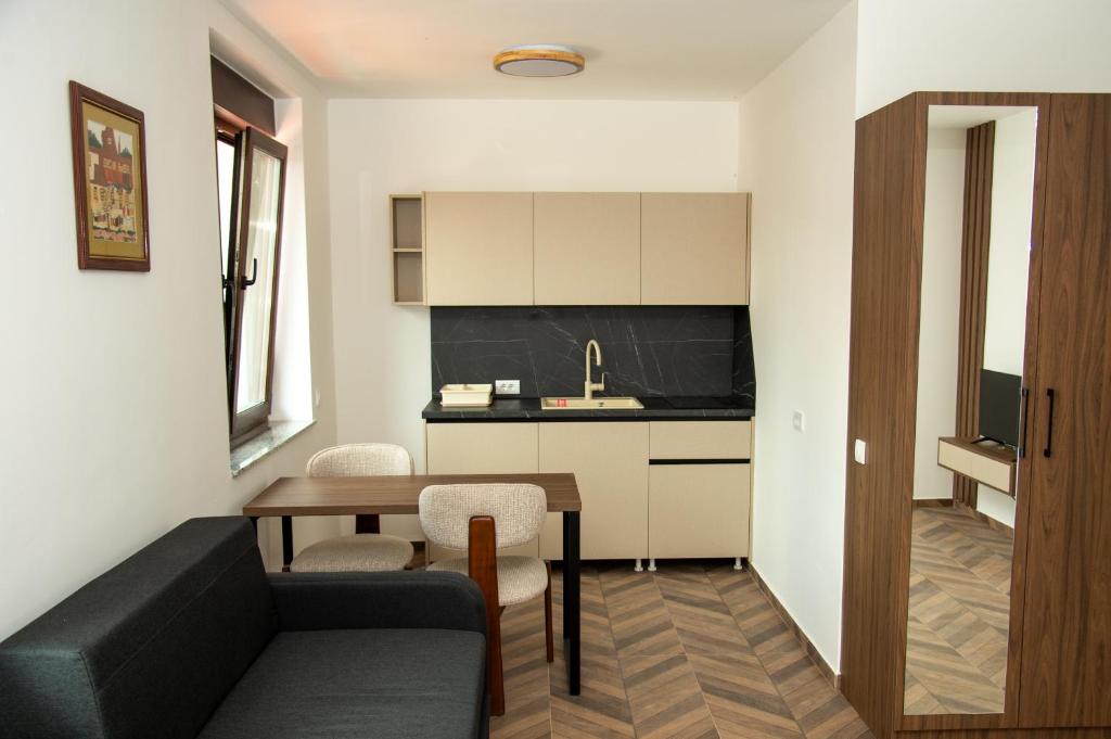 a living room with a black couch and a kitchen at Apartmani Gradska in Prijepolje
