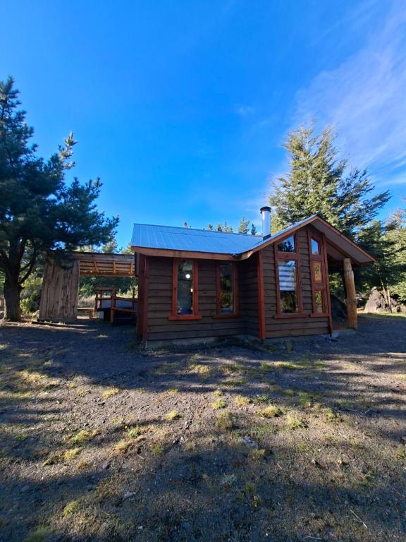 a cabin in a field with trees in the background at Refugio entre Coihues in Melipeuco