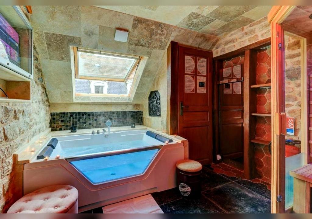 a large bath tub in a bathroom with a window at Sous mon toit - Sauna & jacuzzi in Dijon