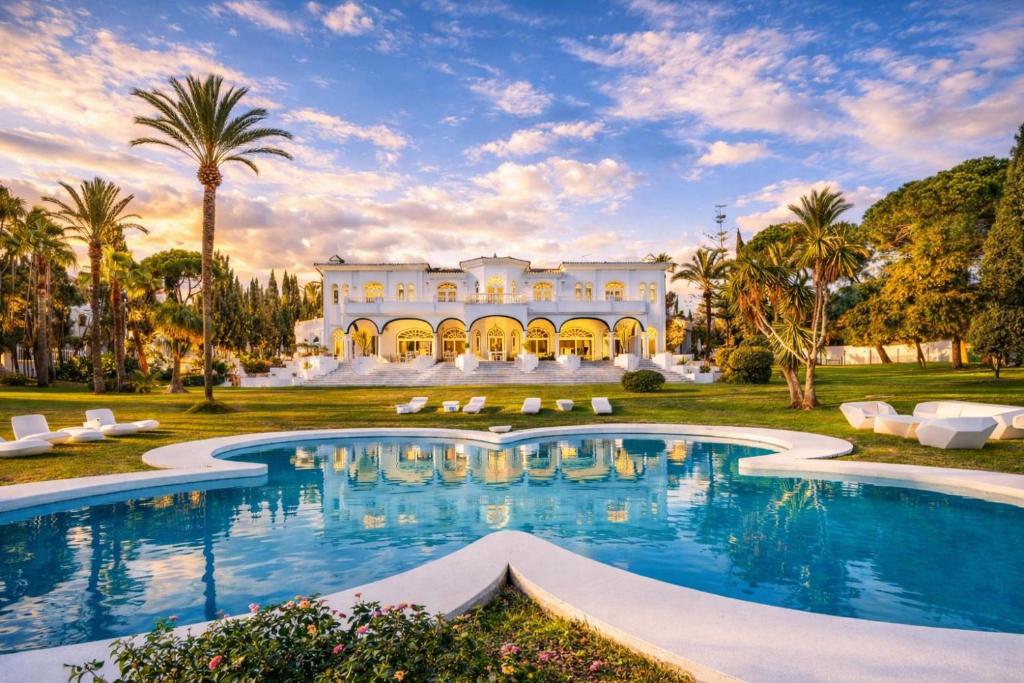 a mansion with a pool and palm trees at Palacio Suites Marbella in Marbella
