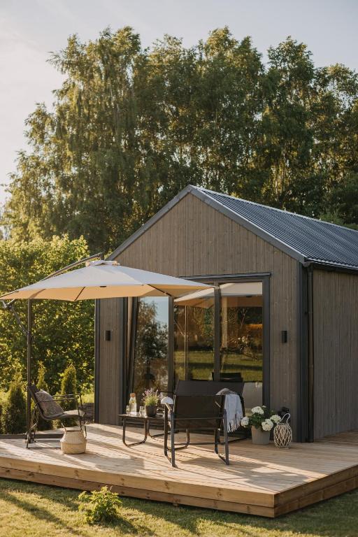 a wooden deck with an umbrella and a table and chairs at Ruoliškis tiny house in Biržai