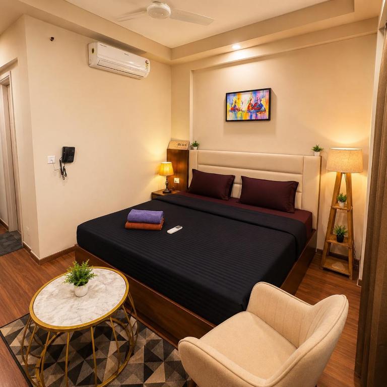 a bedroom with a bed and a chair and a table at Glow Corner in Greater Noida