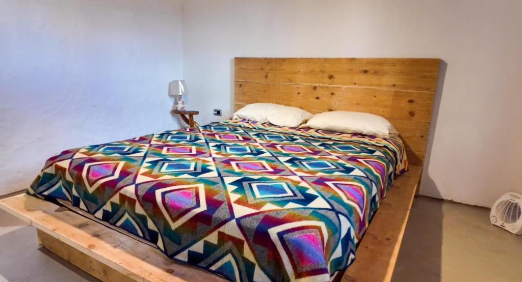 a bed with a wooden headboard and two pillows at Lodge La Ilusión in Ibarra