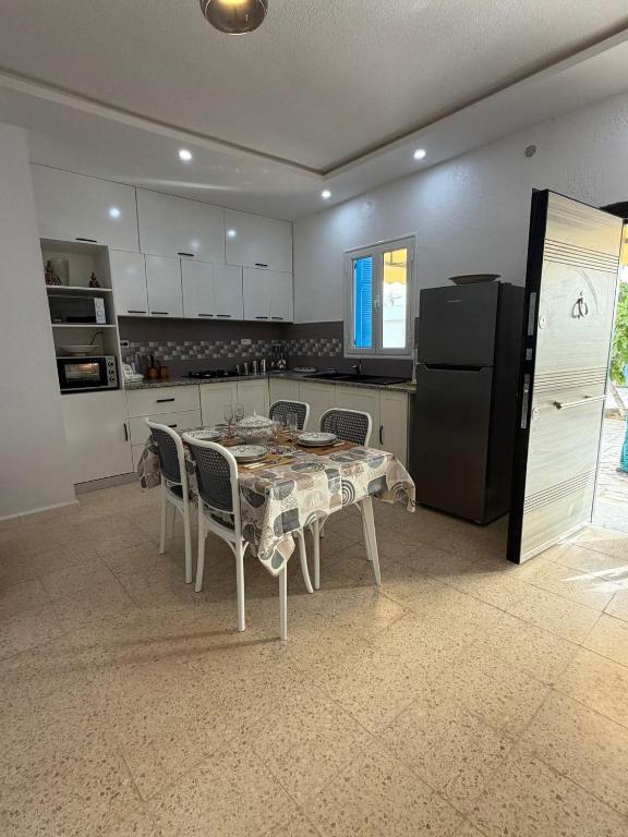 a kitchen with a table with chairs and a refrigerator at Dar Sidi Mohamed in Zarzis