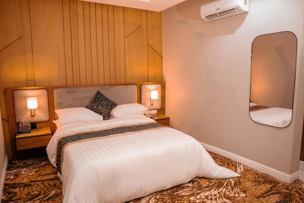 a bedroom with a large bed and a mirror at Swisse International Rancho Valeria Hotel & Suites in Warri