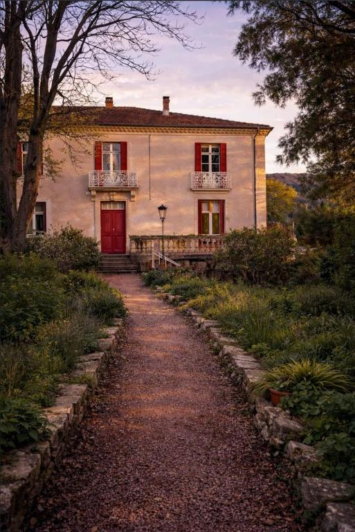 an old house with a red door and a dirt road at villa marguerite in Lunas