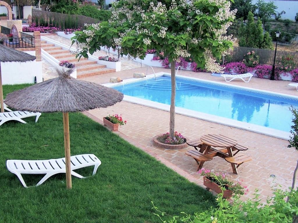 a pool with two chairs and a table and an umbrella at Belvilla by OYO Casa Mi Pepe in Priego de Córdoba