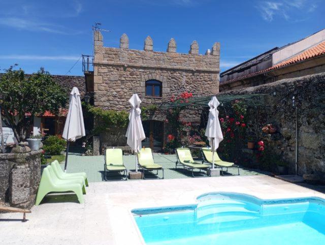 a pool with chairs and umbrellas next to a building at Casa do Torreão in Trancoso